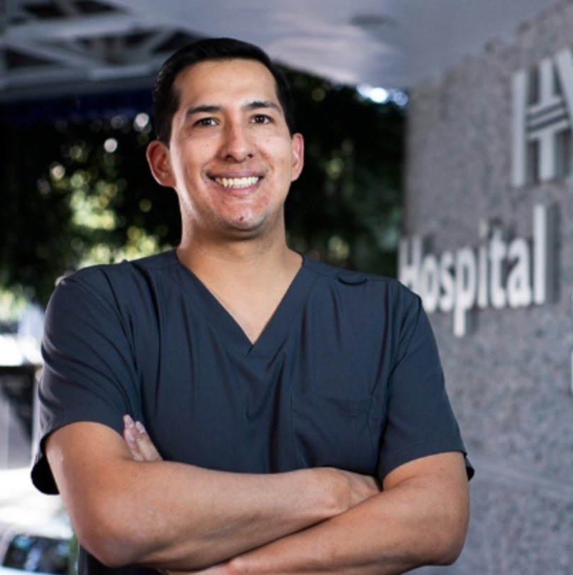 Dr. Marco Diego Sandoval, proctólogo gay friendly, sonriendo con uniforme quirúrgico frente al Hospital Ángeles